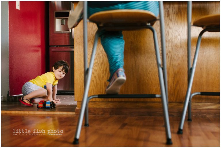 boy plays with trucks on kitchen floor