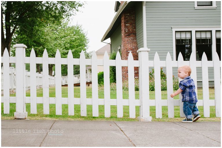 boy walks a long picket fence